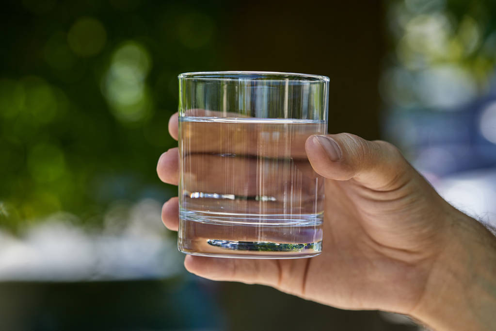 Hand holding a glass of water outdoors